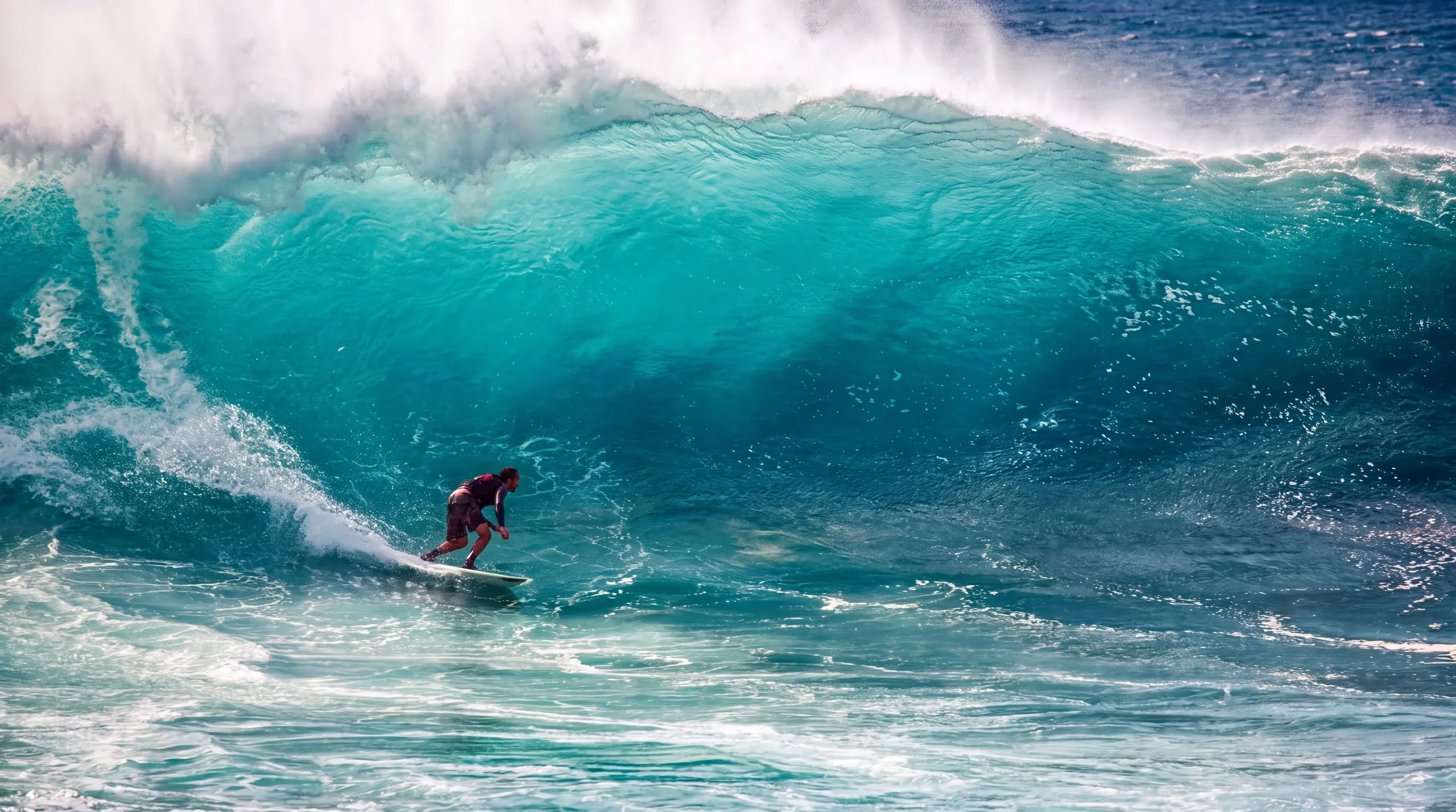 Surfer riding a large turquoise wave