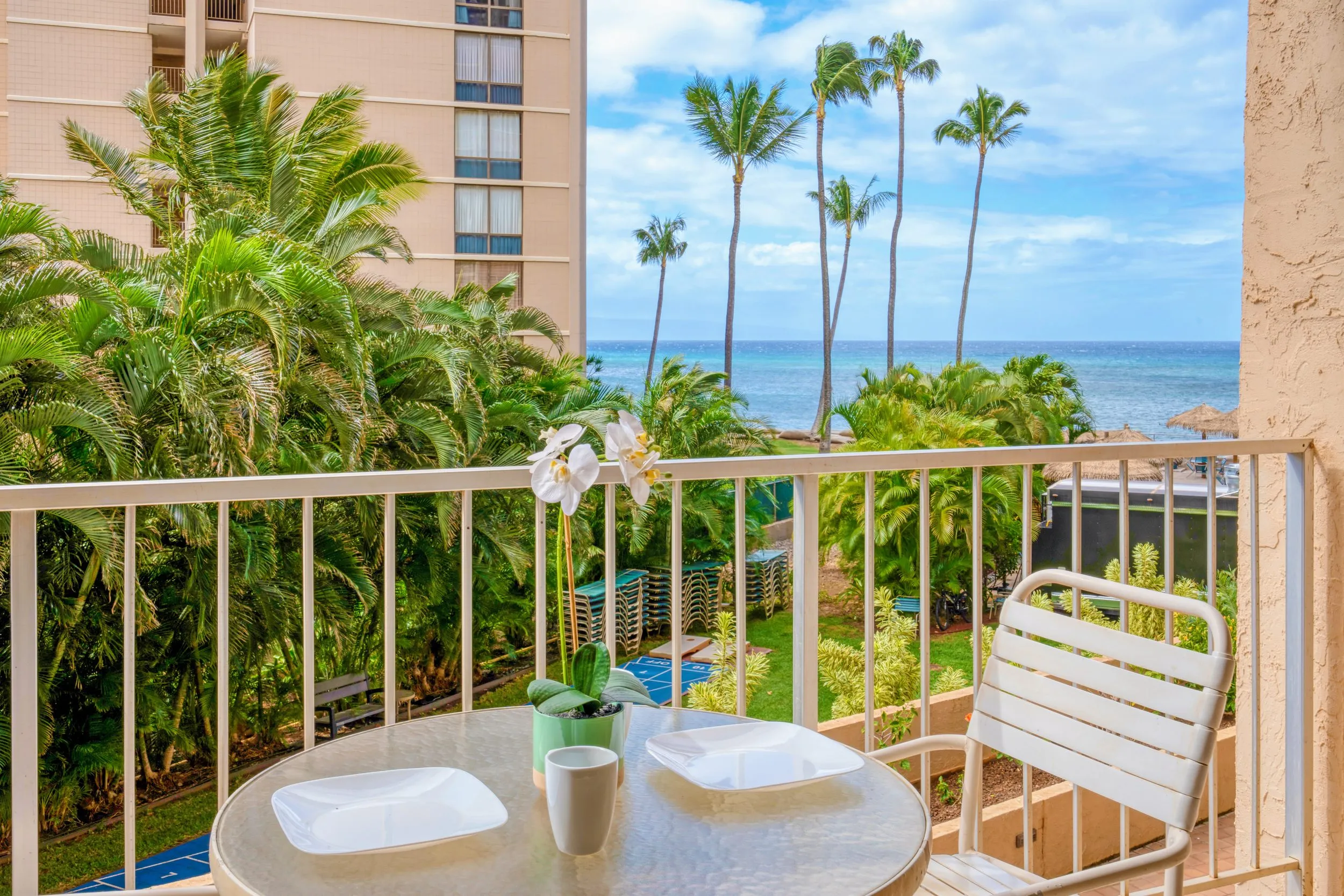Lanai table and chairs with the ocean and palms beyond