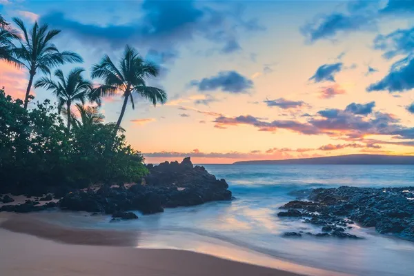 Sunset over the water from a rocky Maui beach